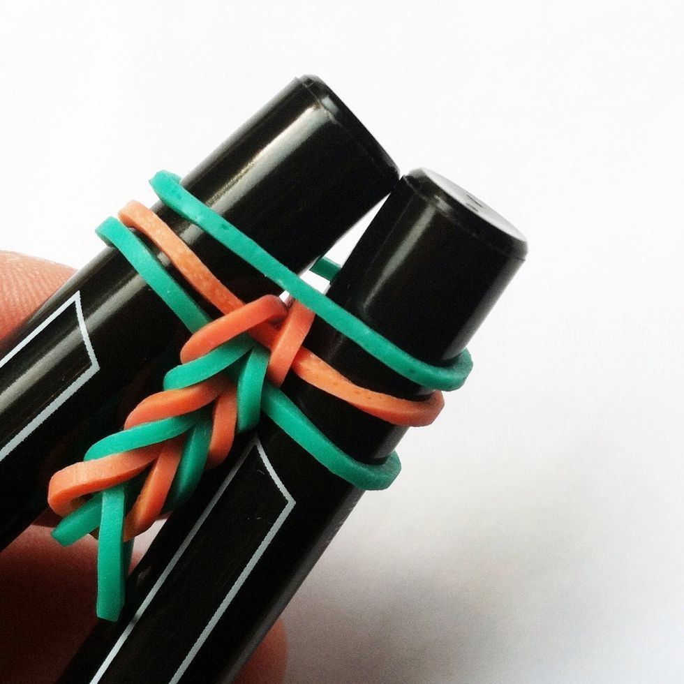 Continue adding one elastic at a time and repeating the process of pulling the elastics over the pens toward the center.