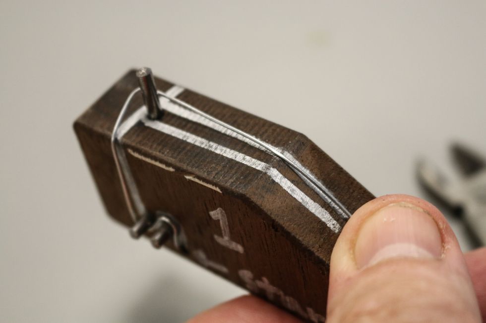 Continue bending. You can see in this image the wire wants to bend up. Press down tight against the pins and corners and it should keep its shape. You'll trim any excess wire when you come to the end.