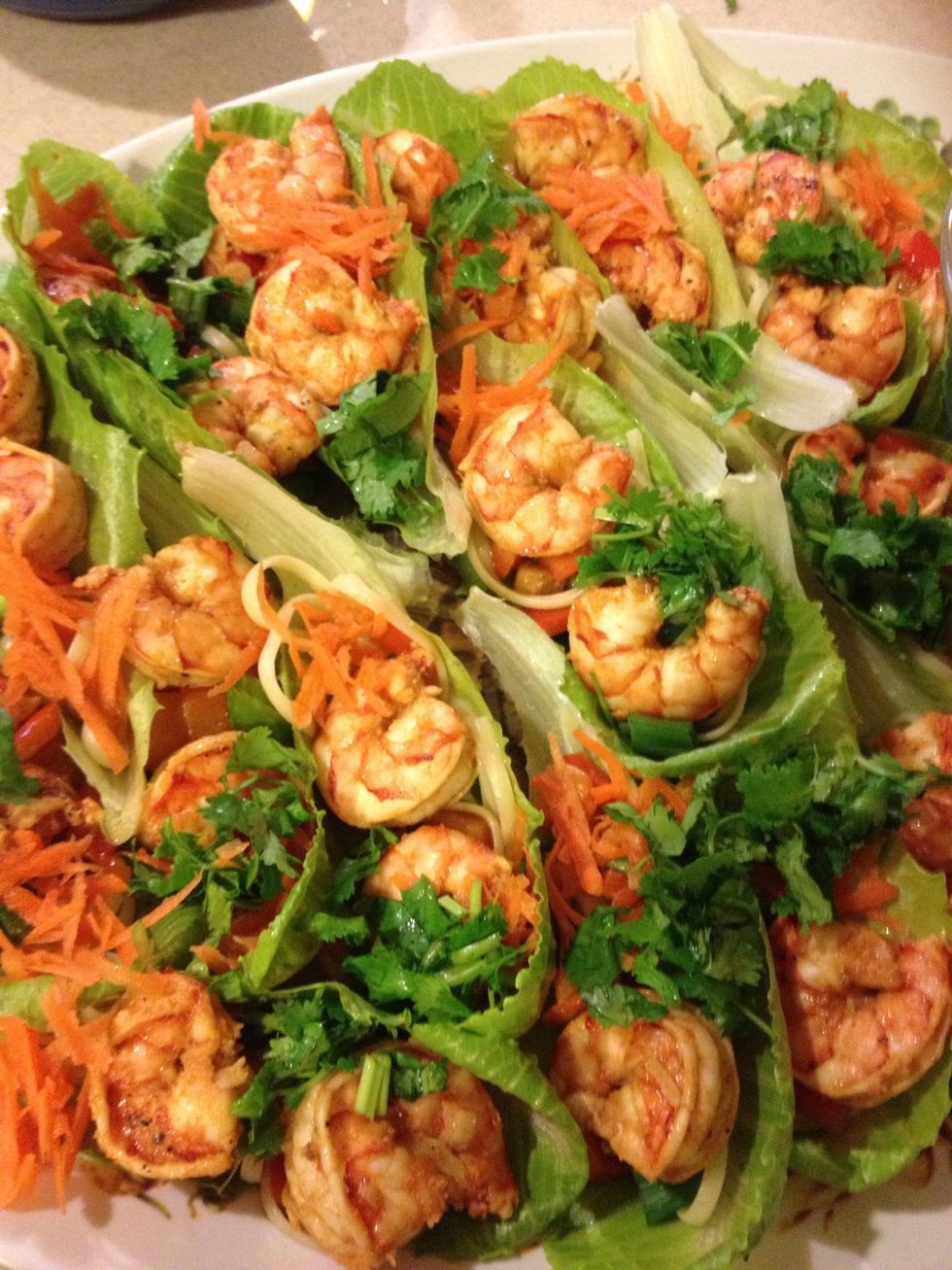 Continue to layer bell pepper, scallions, 2-3 shrimp, carrot, and cilantro onto each leaf. Drizzle with soy sauce.