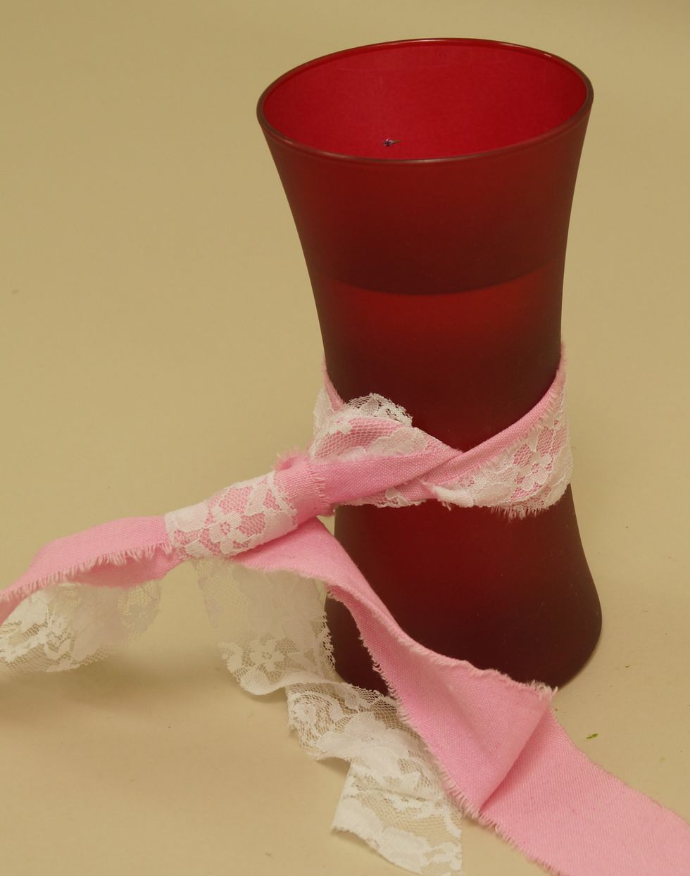 Continue to tie Raw Muslin and White Lace Wrap into a creative knot.