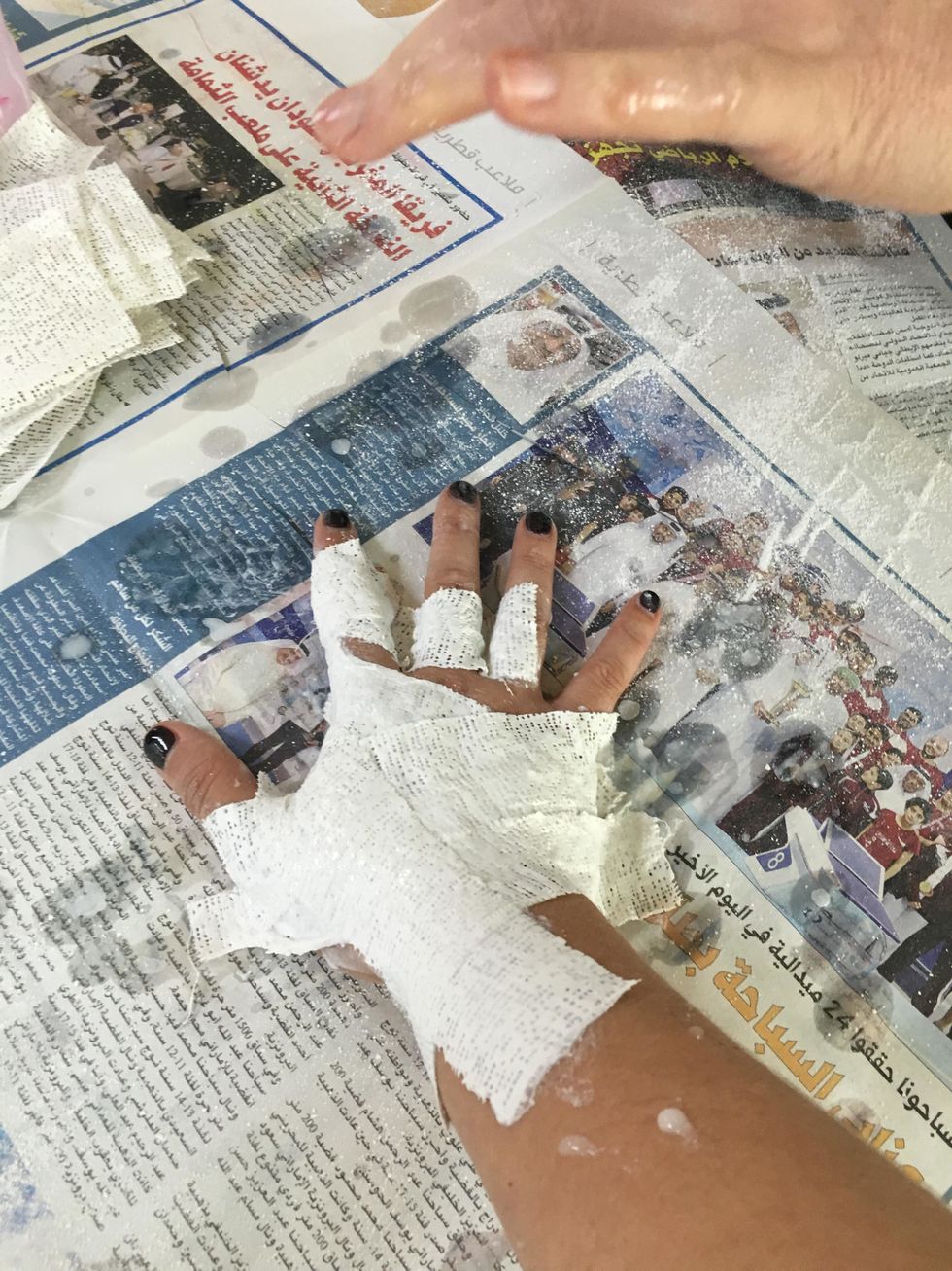 Continue you this until you have two layers of plaster over the hand and wrist. Be sure to smooth out the plaster strips and get in between the fingers.