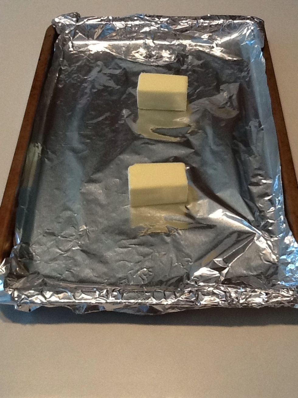 Cover a baking sheet with aluminum foil and place one stick of butter on top.  (I cut mine in half.)  Place pan in preheated oven.