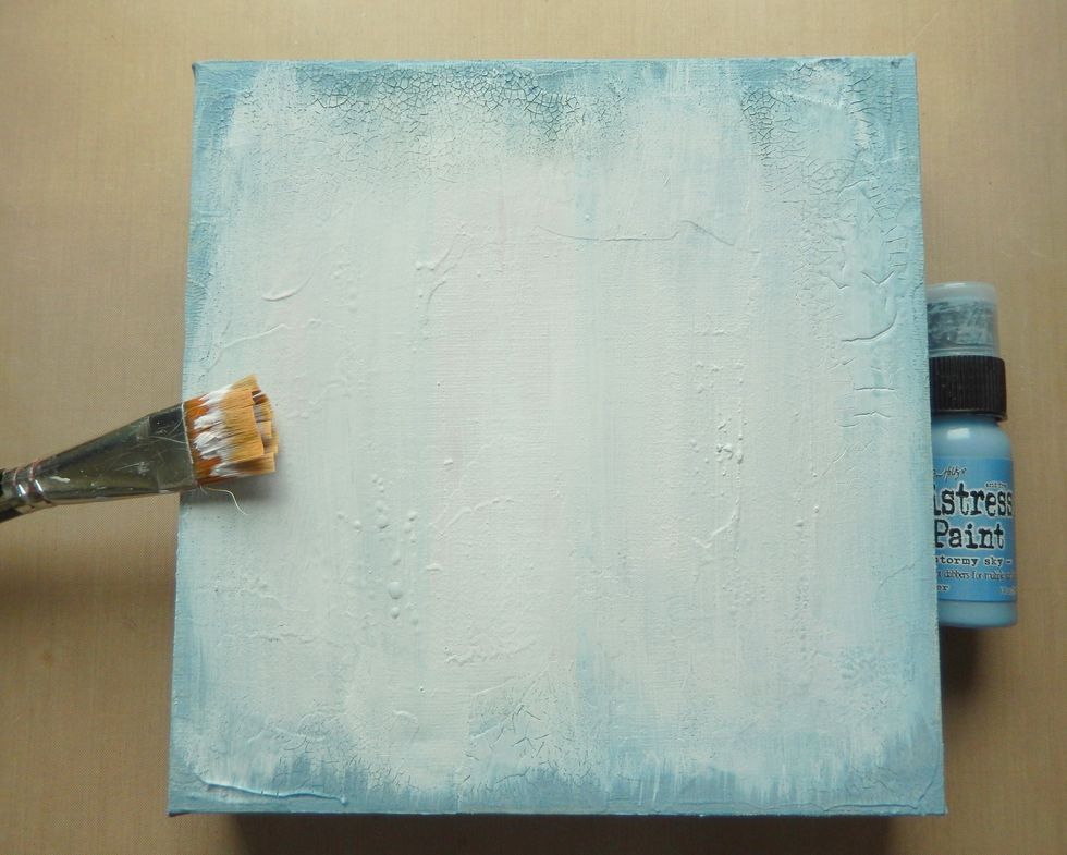 Cover a blank square canvas with a layer of Distress Collage Medium Crazing and allow to dry. Then paint over a layer of Stormy Sky Distress Paint followed by one of white gesso, avoiding the edges.