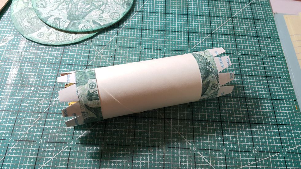 Cover both ends of the toilet tissue roll with an inch of paper, cut shapes ready to fold and adhere as shown.