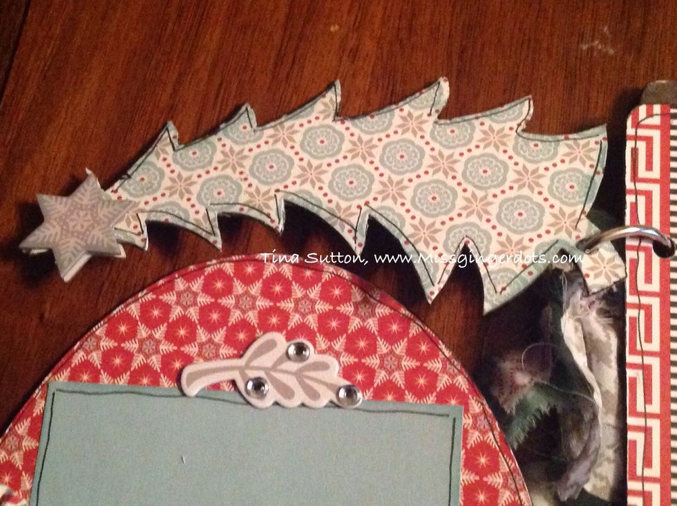 Cover both sides of Christmas tree with blue printed paper! Outline. Add chipboard star from compliments on both side. Add sparkle to middle of star!