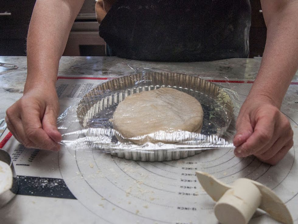 Cover it with plastic wrap, and then using your fingers, push and spread the dough around the bottom and sides of the pan until they're covered.