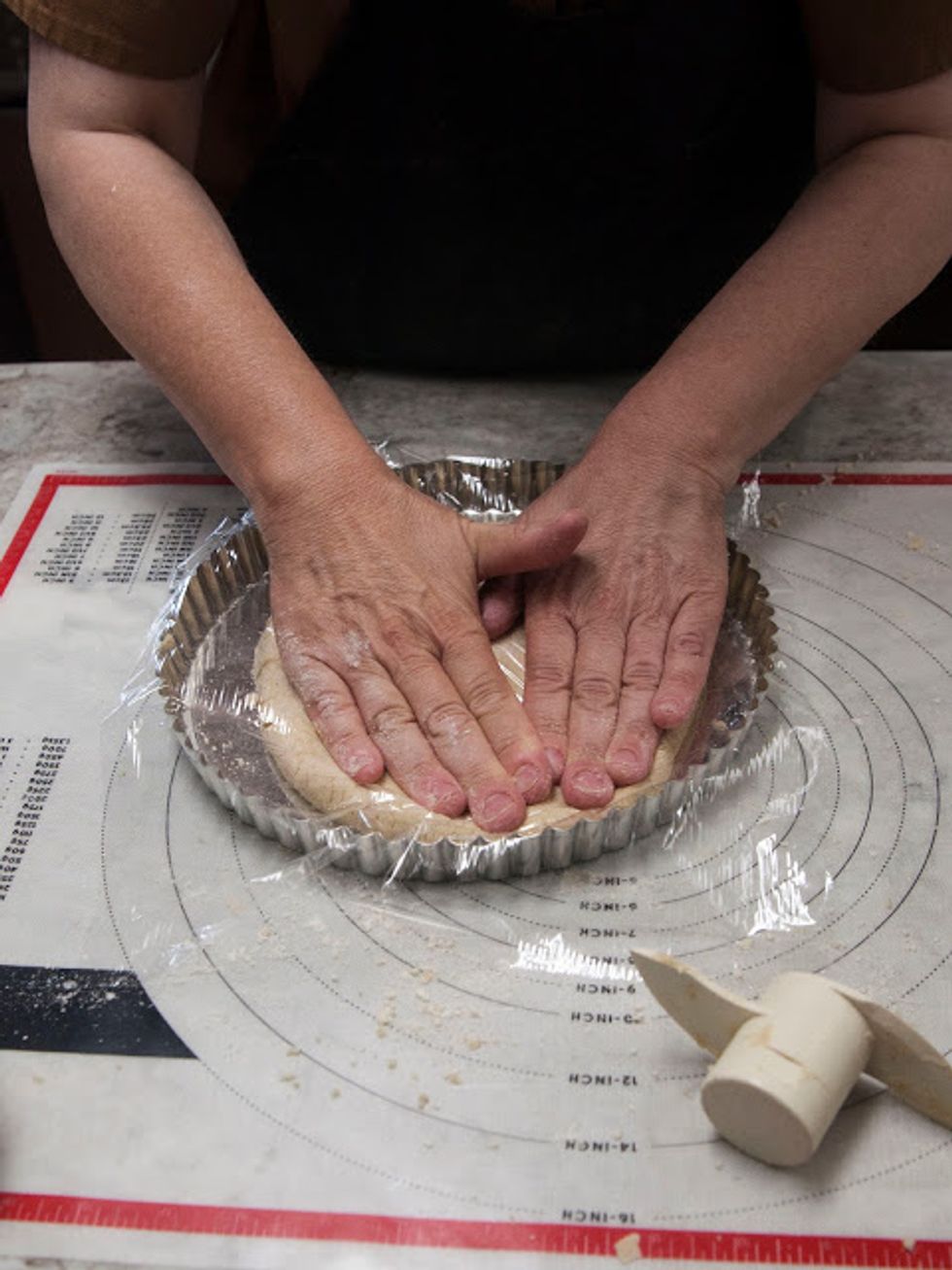 Cover it with plastic wrap, and then using your fingers, push and spread the dough around the bottom and sides of the pan until they're covered.