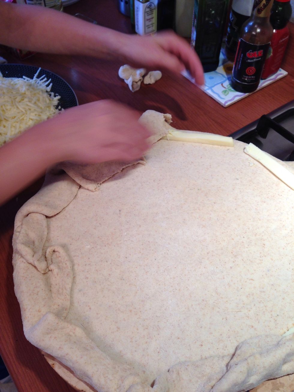 Cover the cheese sticks with the extra dough, forming the stuffed edge