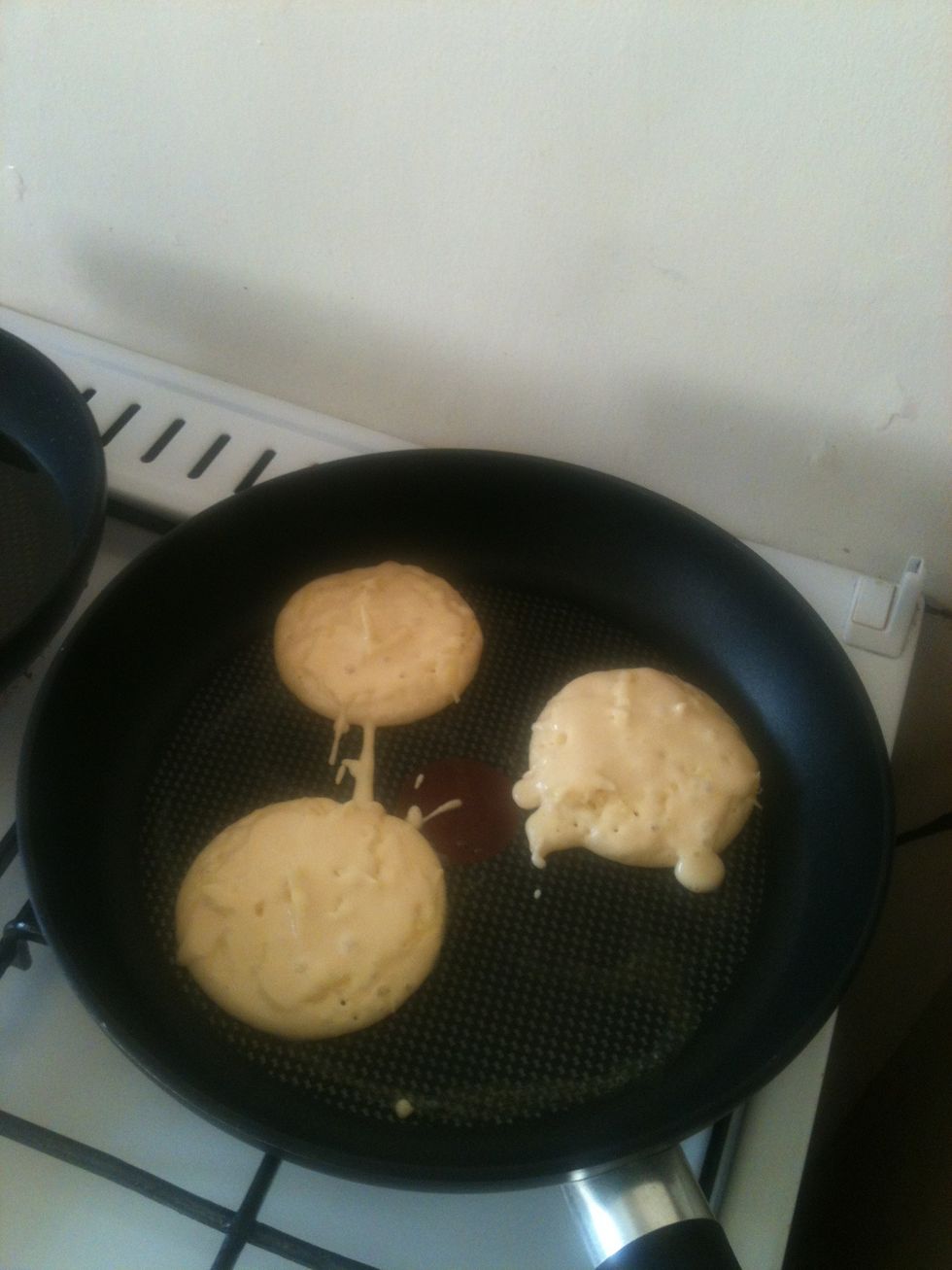 Cover the cheese with a thin layer of batter, so that cheese melts within, and doesn't burn on the pan when you flip it. You'll have to be quick - since they're small, they cook fast.
