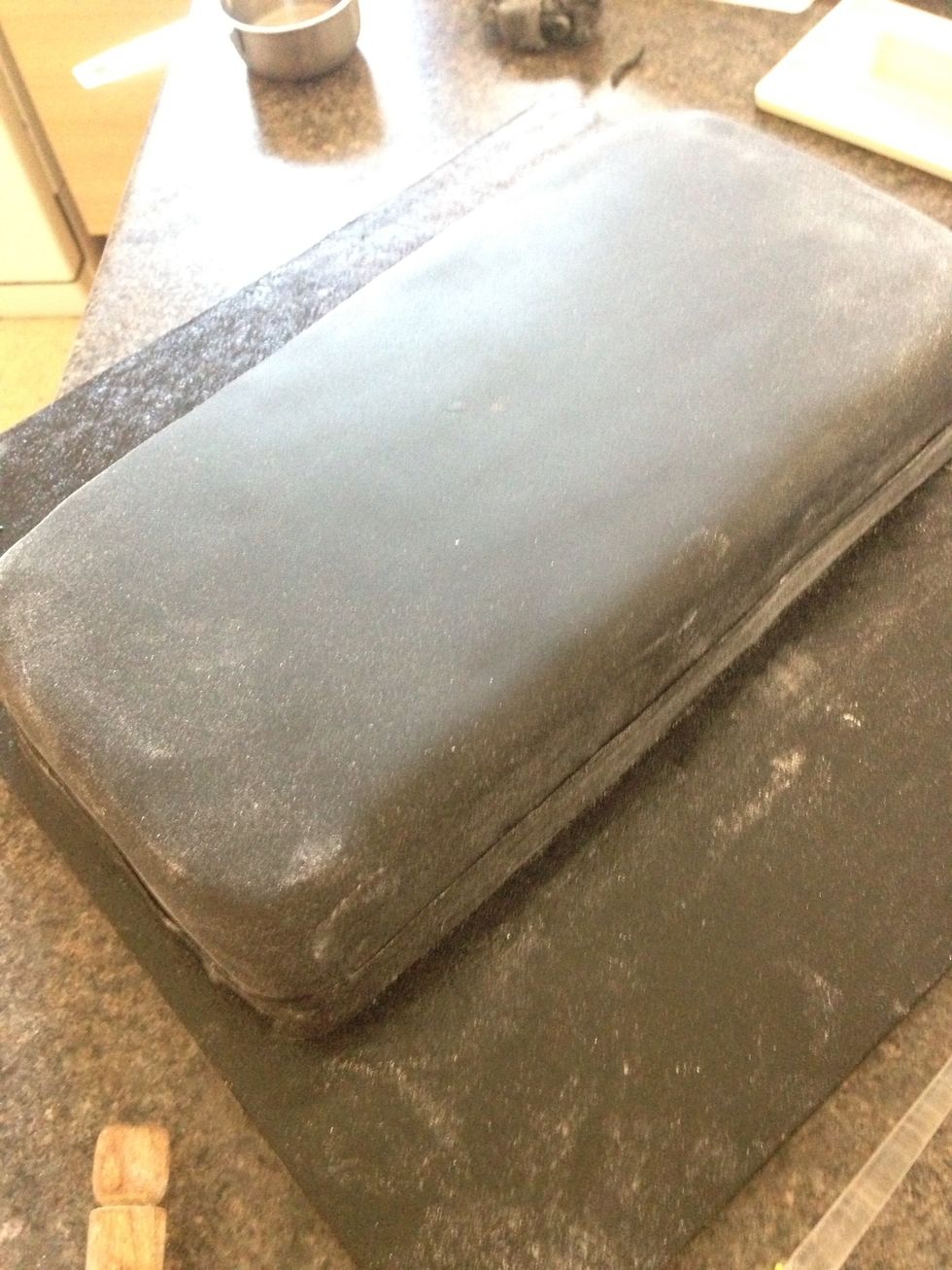 Cover the cooled cake in black fondant. Yes it is black. The icing sugar and the lighting makes it look grey.