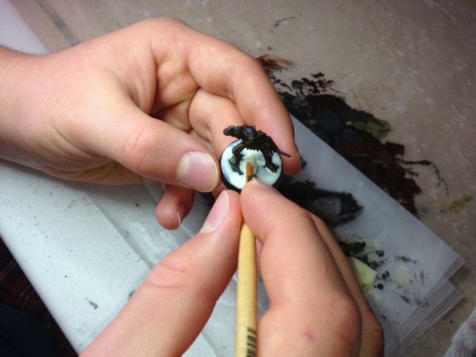 Cover the entire base. It may even help to put a little glue up around the model's feet. This makes it look as though it is not separate from the environment around it.