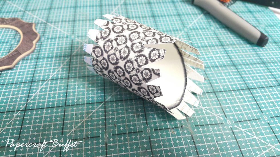 Cover the toilet tissue roll with pattern paper, cut the two ends with gaps, get ready to adhere the chipboard piece on and on the bar cart.