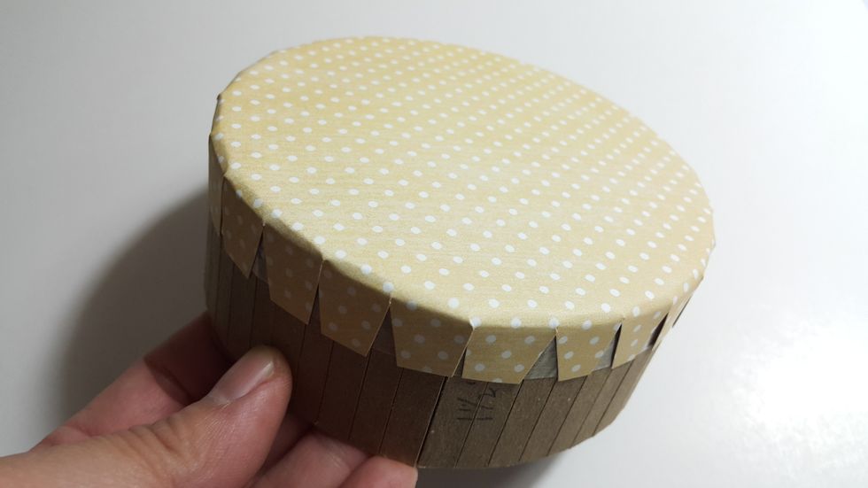 Cover the top with a layer of cotton (optional) and then 3" radius circle paper, fold and adhere the half inch edges as shown