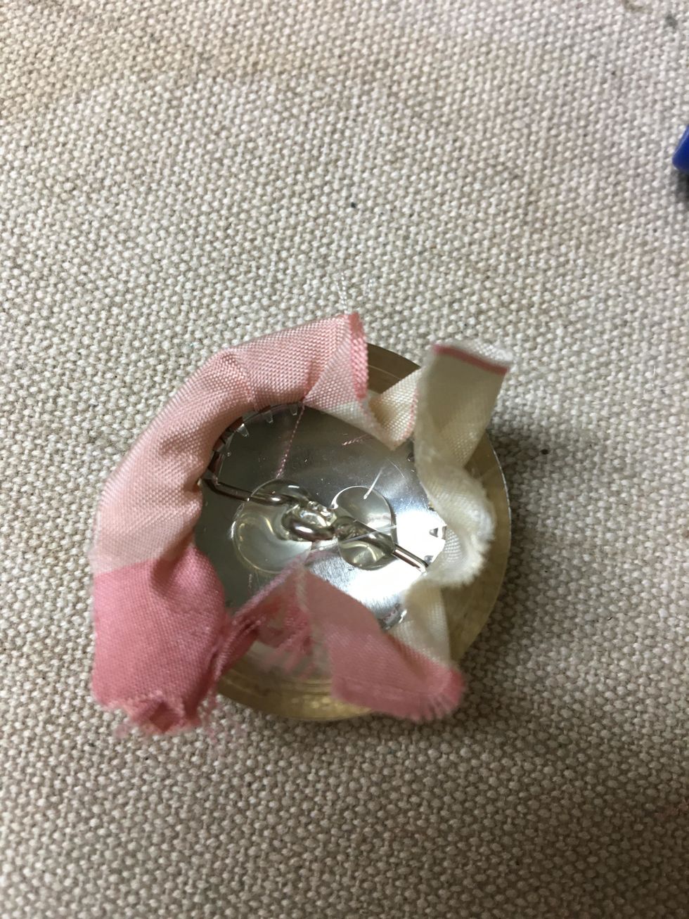 Cover your buttons with fabric. Fill the button with a little hot glue before clicking the back onto it. This helps the pin to stay secure after they are pulled into the tuft of the cushion