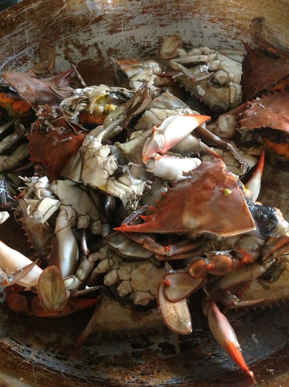 Crabs halved and added to the pan. Toss them to coat in the curry paste and oil. Then add the ginger and lemongrass.