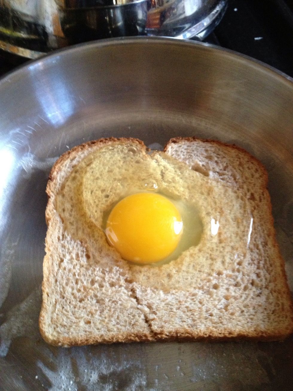 Crack an egg and place it in the hole