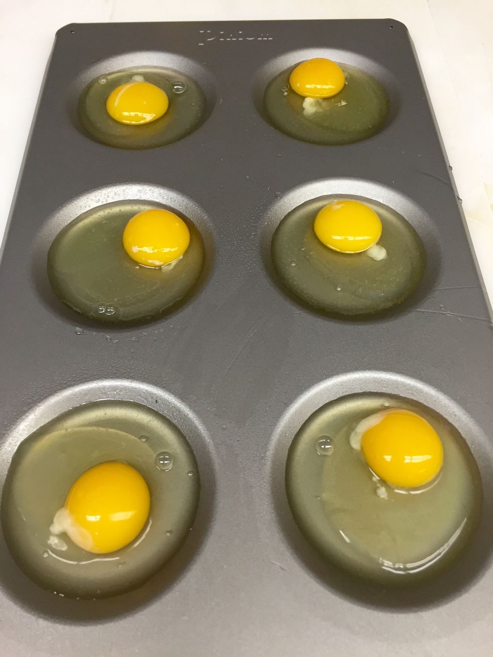Crack eggs into each well.