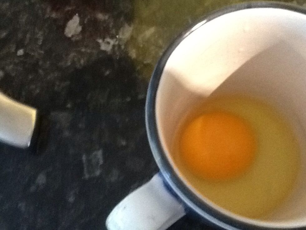 Crack open an egg into a small cup.
