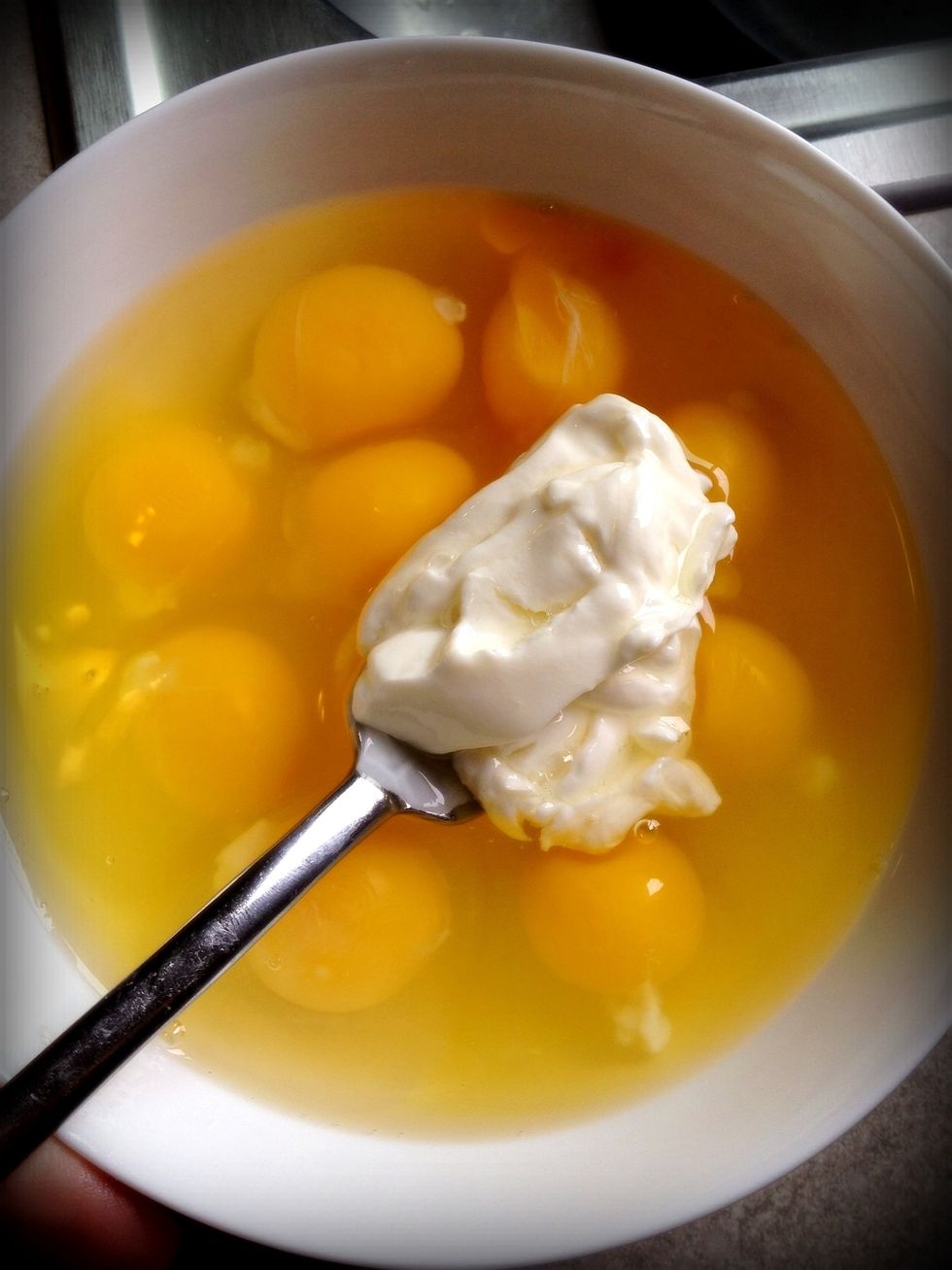 Crack the eggs and add a spoonful of sour cream. Whisk with a fork.