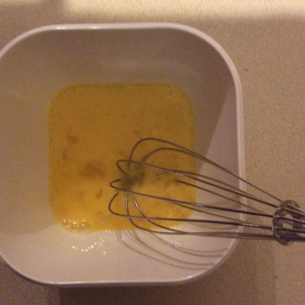 Crack two eggs into a bowl, then whisk them together, so it becomes a dark yellow