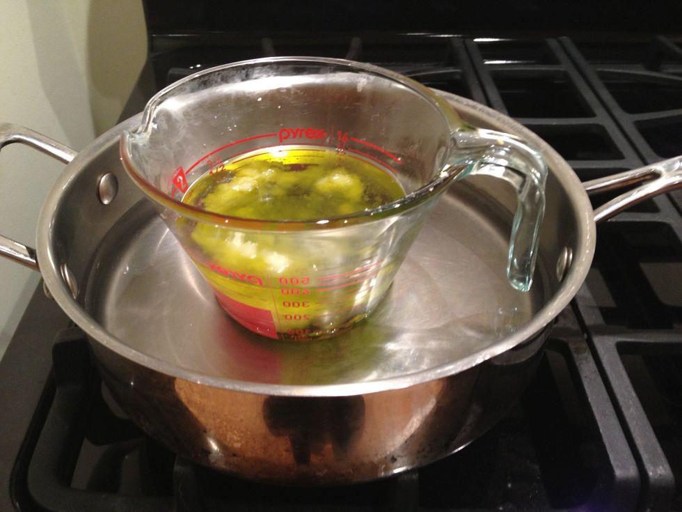 Create a double boiler by placing the Pyrex measuring cup in a pot of water. Slowly melt the mixture over medium heat.