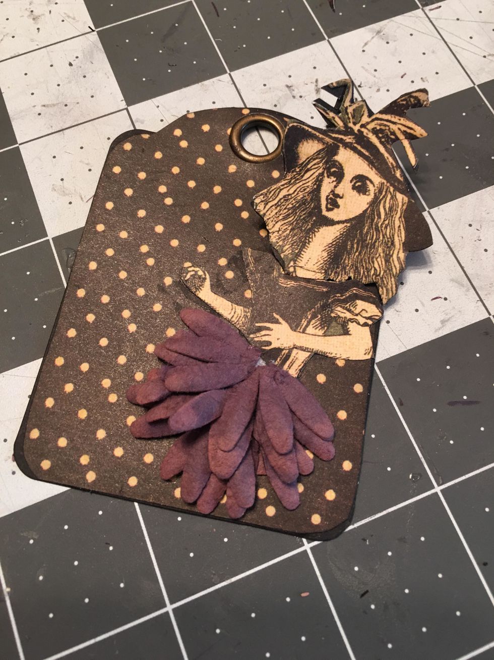 Create a fun element on a tag page with the "spooky Alice" by creating a skirt out of flowers cut in half and folding her long neck so that it unfolds....