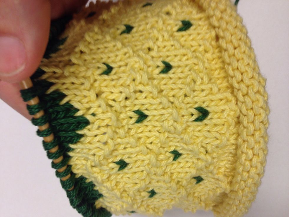 Create the "leaves" at the top of the hat by knitting one green stitch every 8th stitch, then every 7th, 8th and 1st stitch...continuing the "v" until the leaves connect.