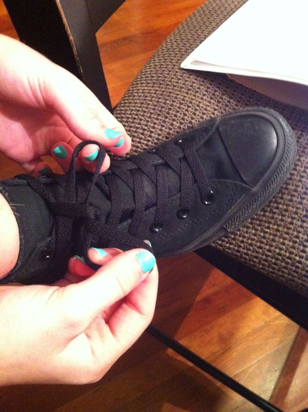 Cross that string in front of the previously made loop and put it through the hole made with the string you just pulled around the loop, creating a second loop