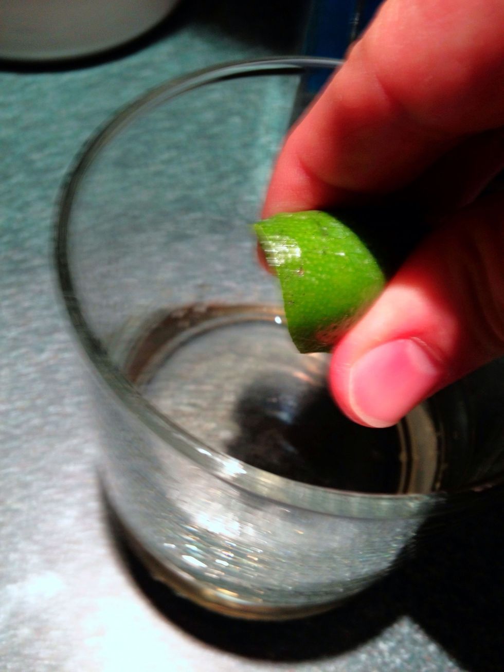 Crush the thin disc of lime into the glass and drop the disc in.