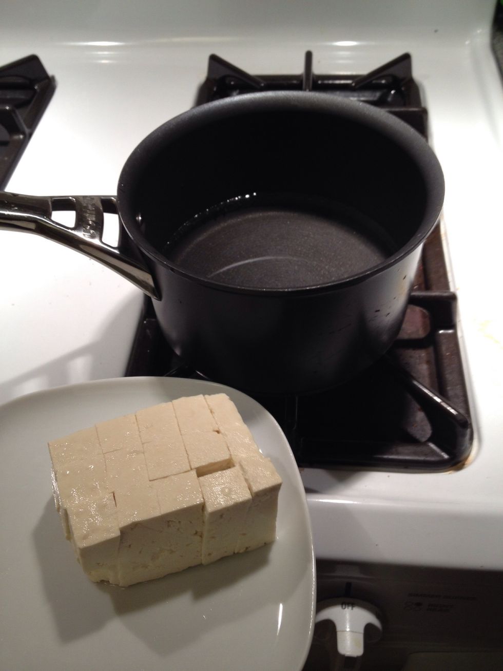 Cut 1/2 block of tofu into cubes and put into the pan with 4 cups of water. Turn temperature to high.