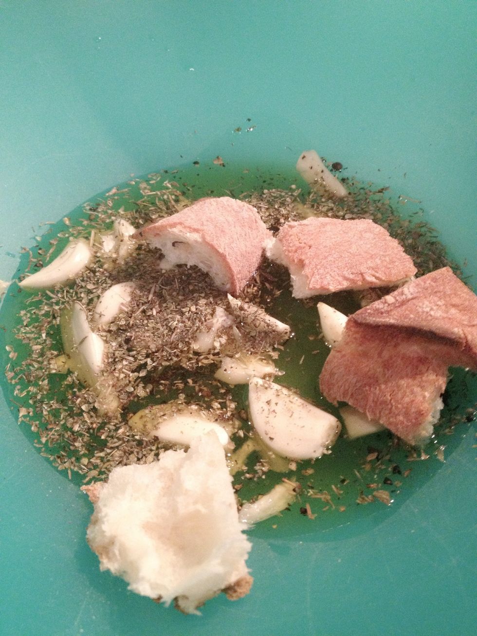 Cut 5 cloves of garlic into strips and put the garlics in a mixing bowl. Add a couple pinches of salt and pepper, oil, thyme, and Italian seasoning into the mixing bowl.