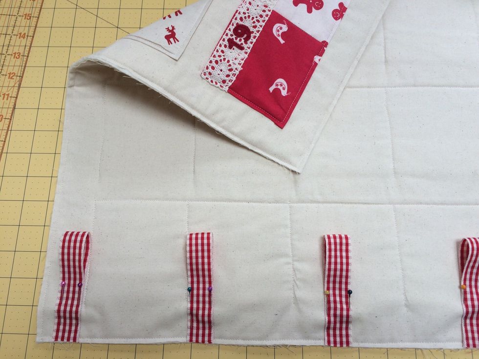 Cut 6 lengths of ribbon x 8 inches. Fold in half and pin raw edges to the top of the back . The outer 2 placed .50 inch from sides and the rest spaced evenly between. Roughly 4 inches apart