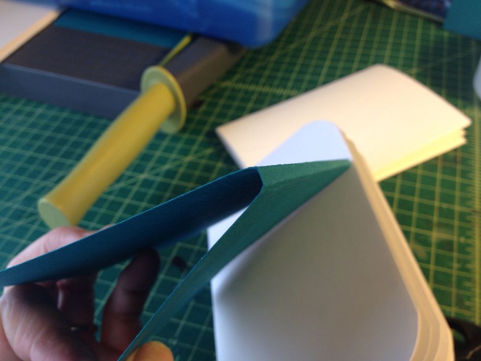 Cut a cover out of card stock. Make it slightly bigger than the booklets. Make two creases on the spine so it matches the thickness of the book's pages.