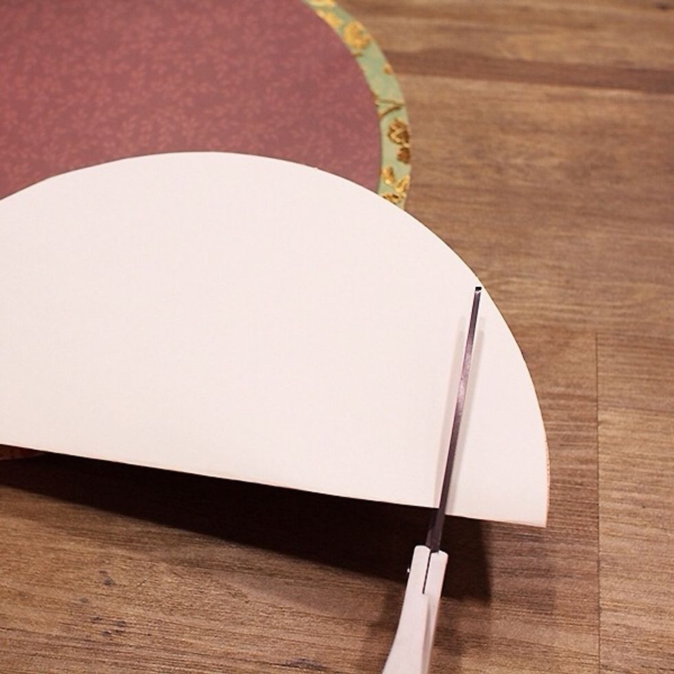 Cut a large circle into each of the 12\u00d712 cardstock craft papers. Fold in half and cut off about an inch of the bottom to create the flat bottom of the pumpkin.
