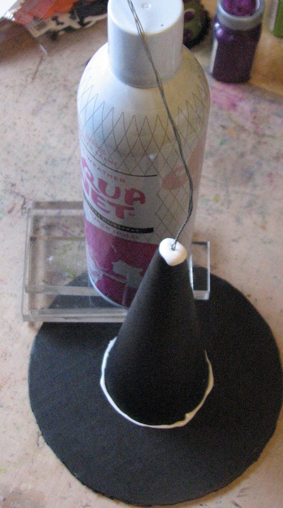 Cut a length of wire about 2 1/2 times the size you want your curly-q to be.  Fold the wire over so it is doubled.  Stick it into the hole of the knitting cone, add lots of glue and let dry.