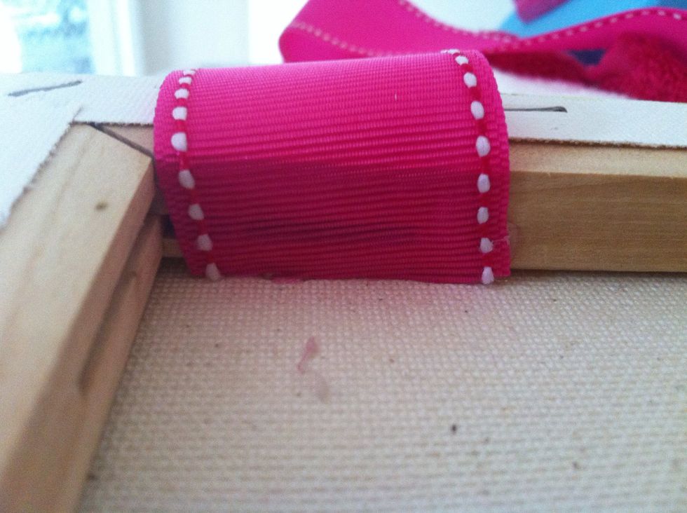 Cut a long enough piece of ribbon. Apply hot glue to the very edges and affix them to the insides of your canvas, pressing down by rolling a pencil eraser over the glue (it is hot!).