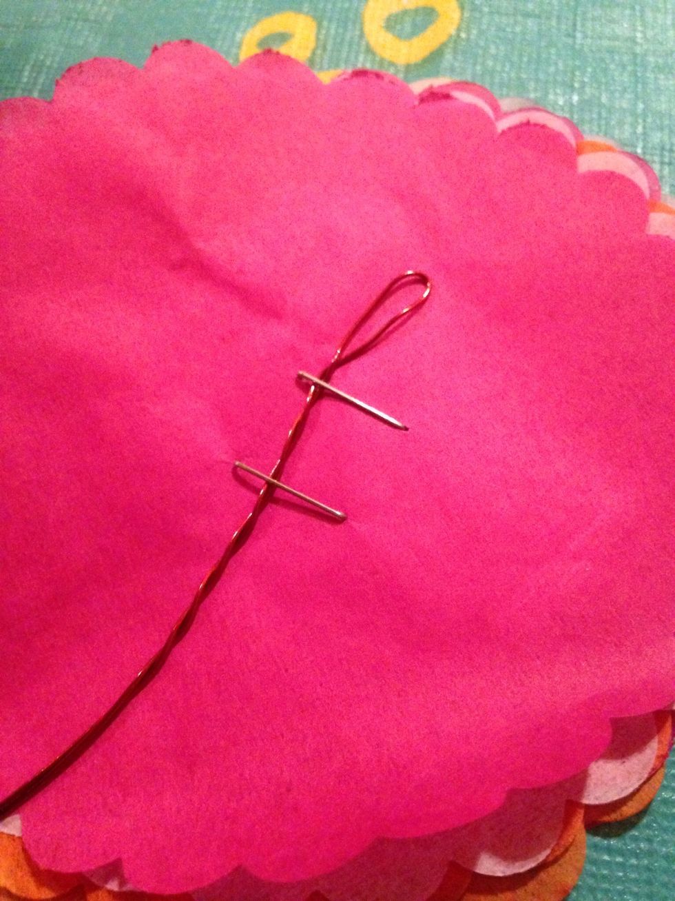 Cut a long piece of wire, double it over and twist.  After gathering eight scallops together staple in the middle while also stapling down the wire.  This will be the 'back' of the flower.