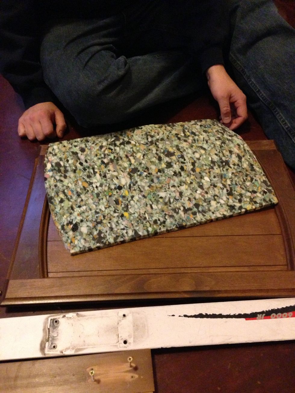 Cut a piece of carpet padding to fit on top of your cupboard door.
