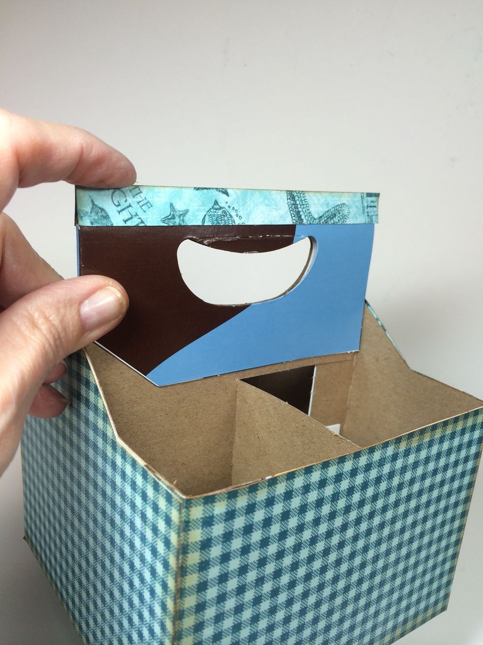 Cut a piece of My Anchor paper 1" x 4 7/8" and fold lengthwise showing the light blue side. Adhere to top handle area of box.
