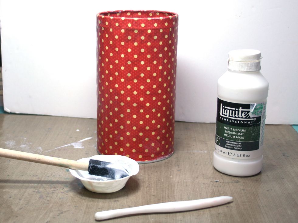 Cut a piece of paper 1/2" longer than the girth of your can & 2"  longer.   Brush matte medium on both the can and the back of the paper.  Adhere to the can tucking the extra 2" length inside the can.