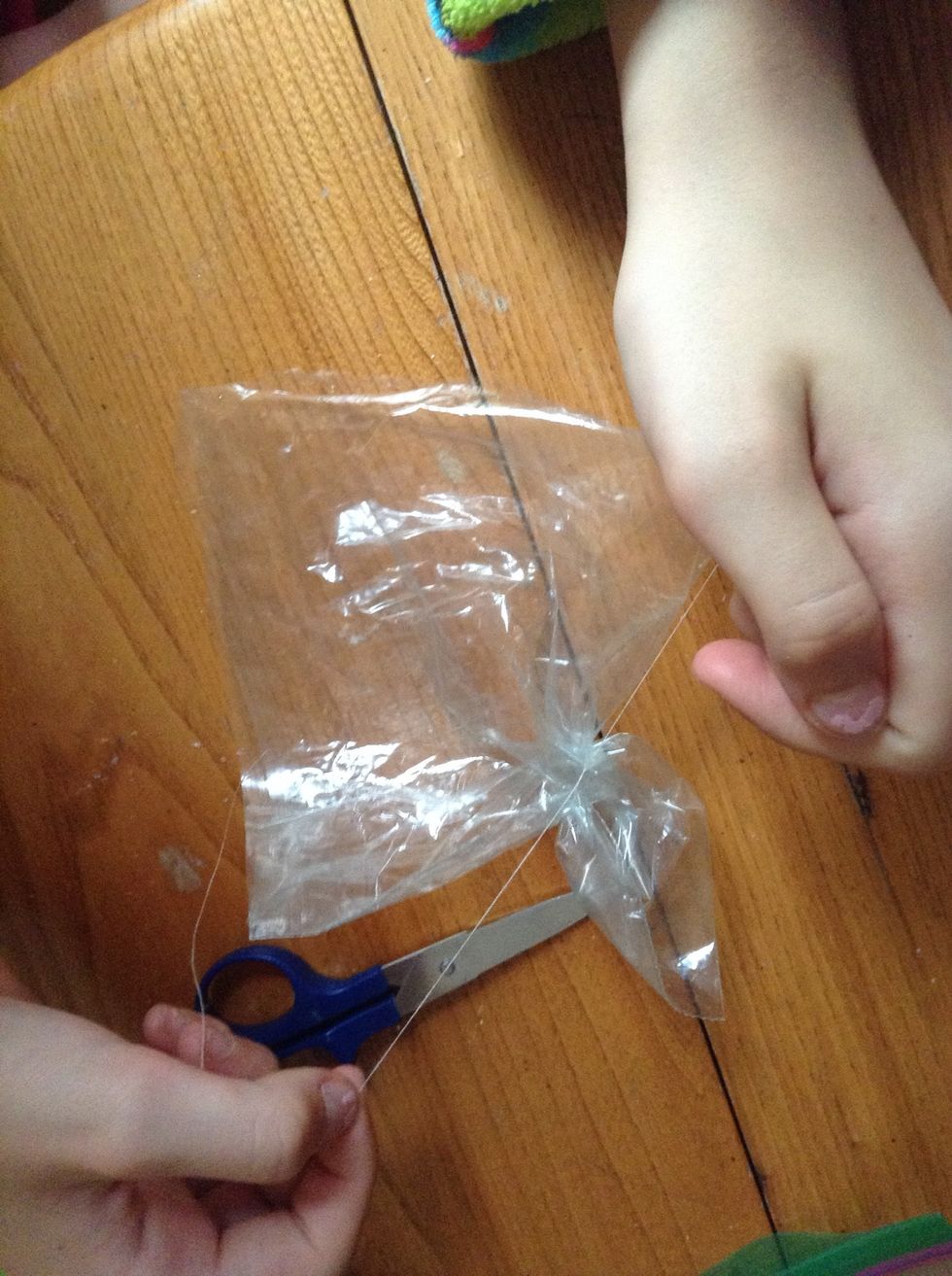 Cut a piece of thread and tie a double knot around so it will start to look like a squid