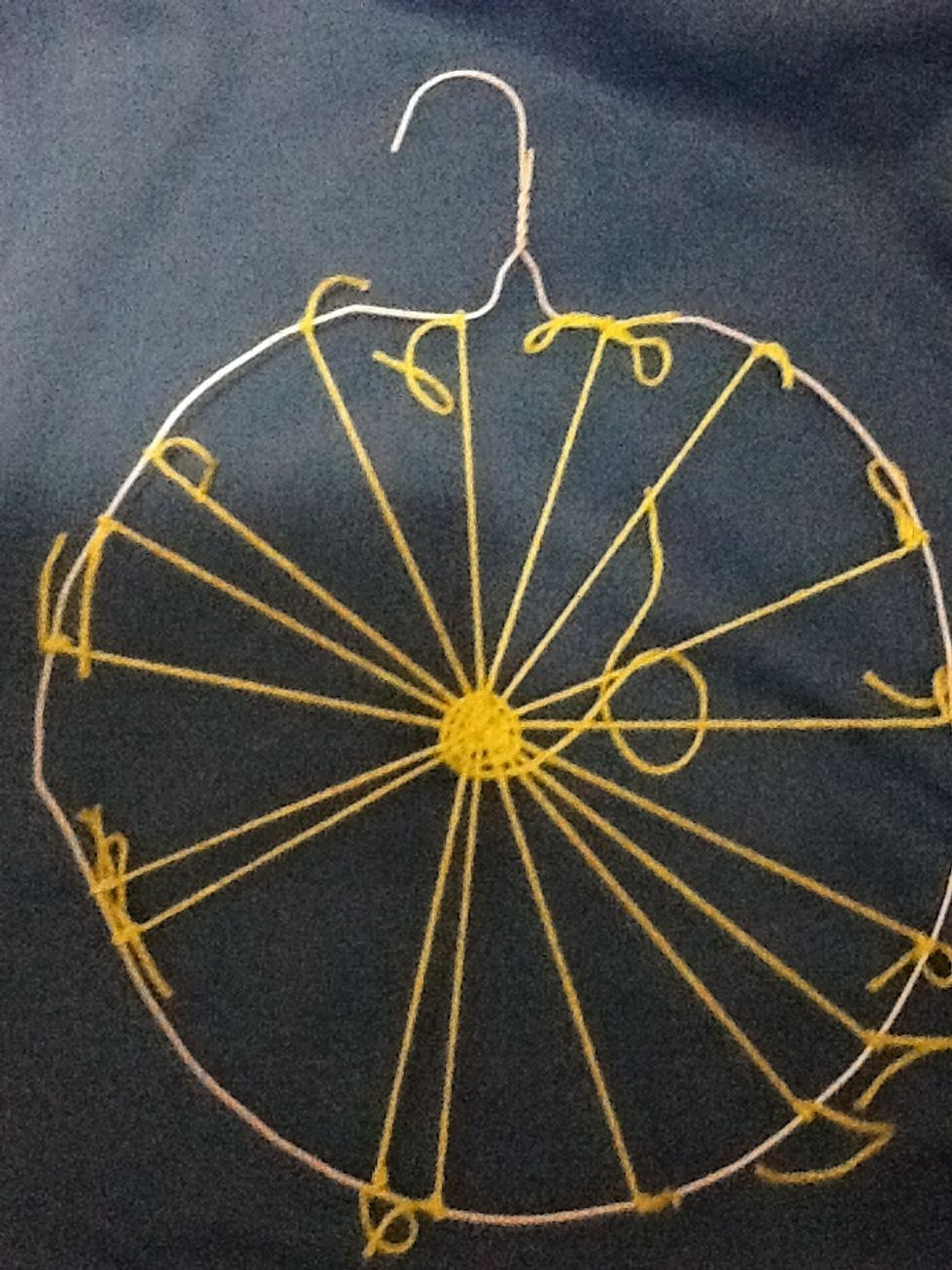 Cut a piece of yarn and tie it to the center of the loom. Weave under and over the spokes around the loom.