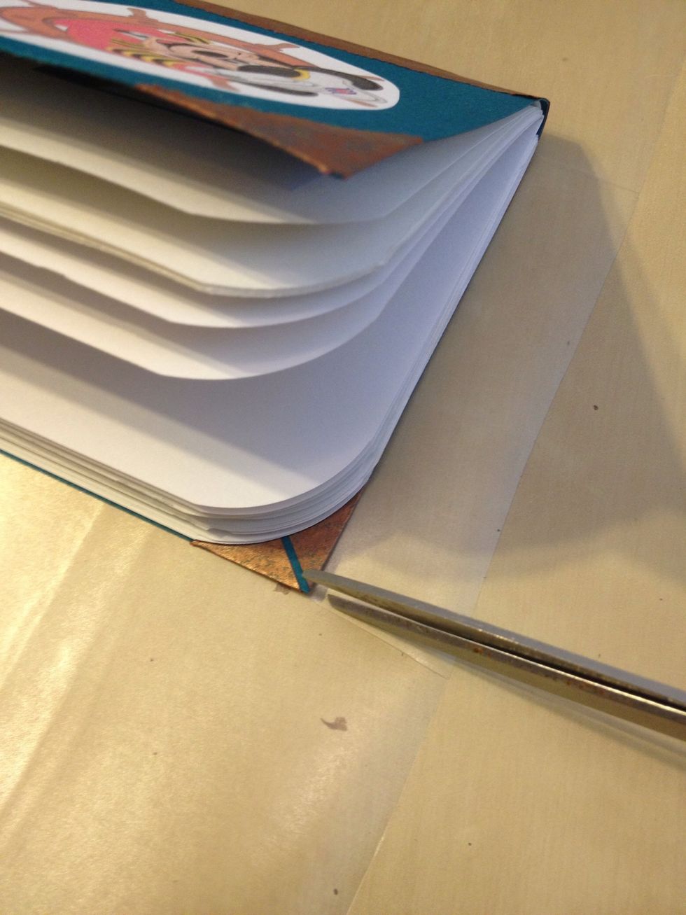Cut a slit on the con-tac paper along the top edge up to the book at the spine, and then another slit up to one corner.