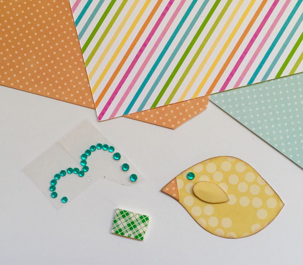 Cut a small triangle of orange paper for the beak and add a jewel for an eye. Then use a little foam tape to adhere the wing and give it some lift.