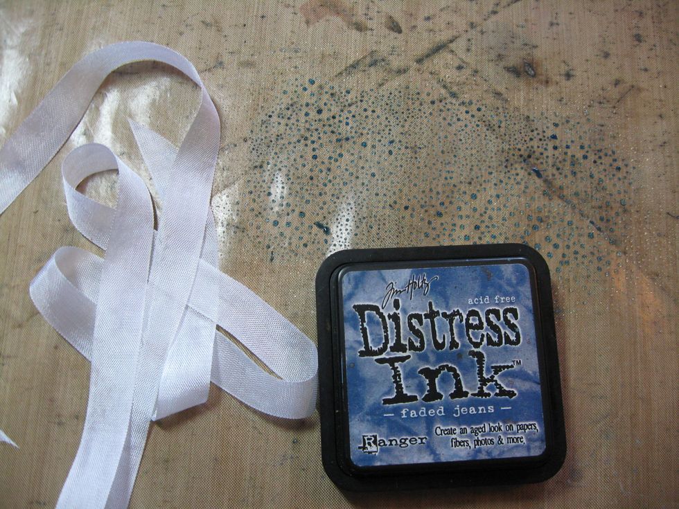Cut a two yard length of white seam binding. Smoosh Distress ink onto non-stick craft sheet and spritz with water. Drag the ribbon through the puddle of ink, moving it around to pick up all the ink.