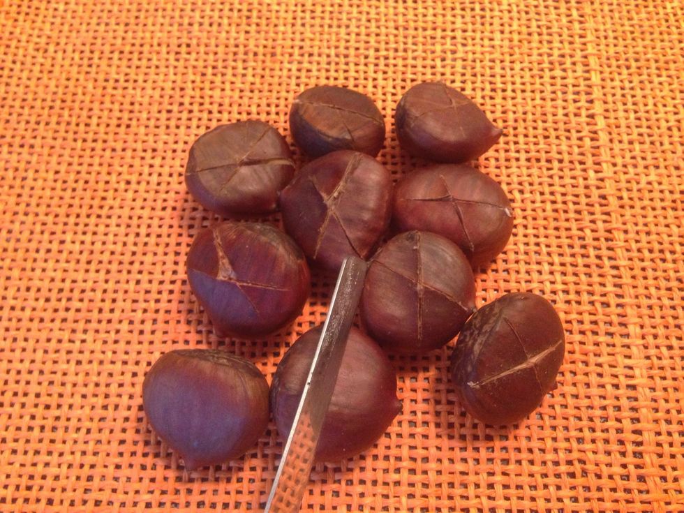 Cut an "X" into the flat side of each chestnut using a pairing or sharp knife. Cut through the shell of the chestnut. This allows them to expand (or they'd burst open) and makes them roast faster.