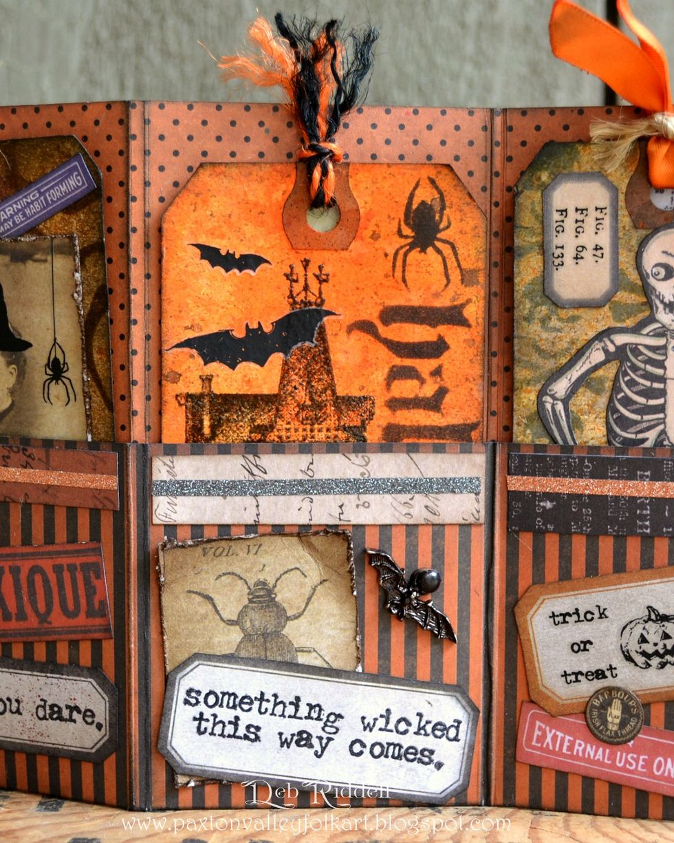 Cut another paper strip, label and the insect image from Regions Beyond paper. Layer the strip with black Halloween Deco sheet. Colour the bat charm with black alcohol ink and secure with a brad.