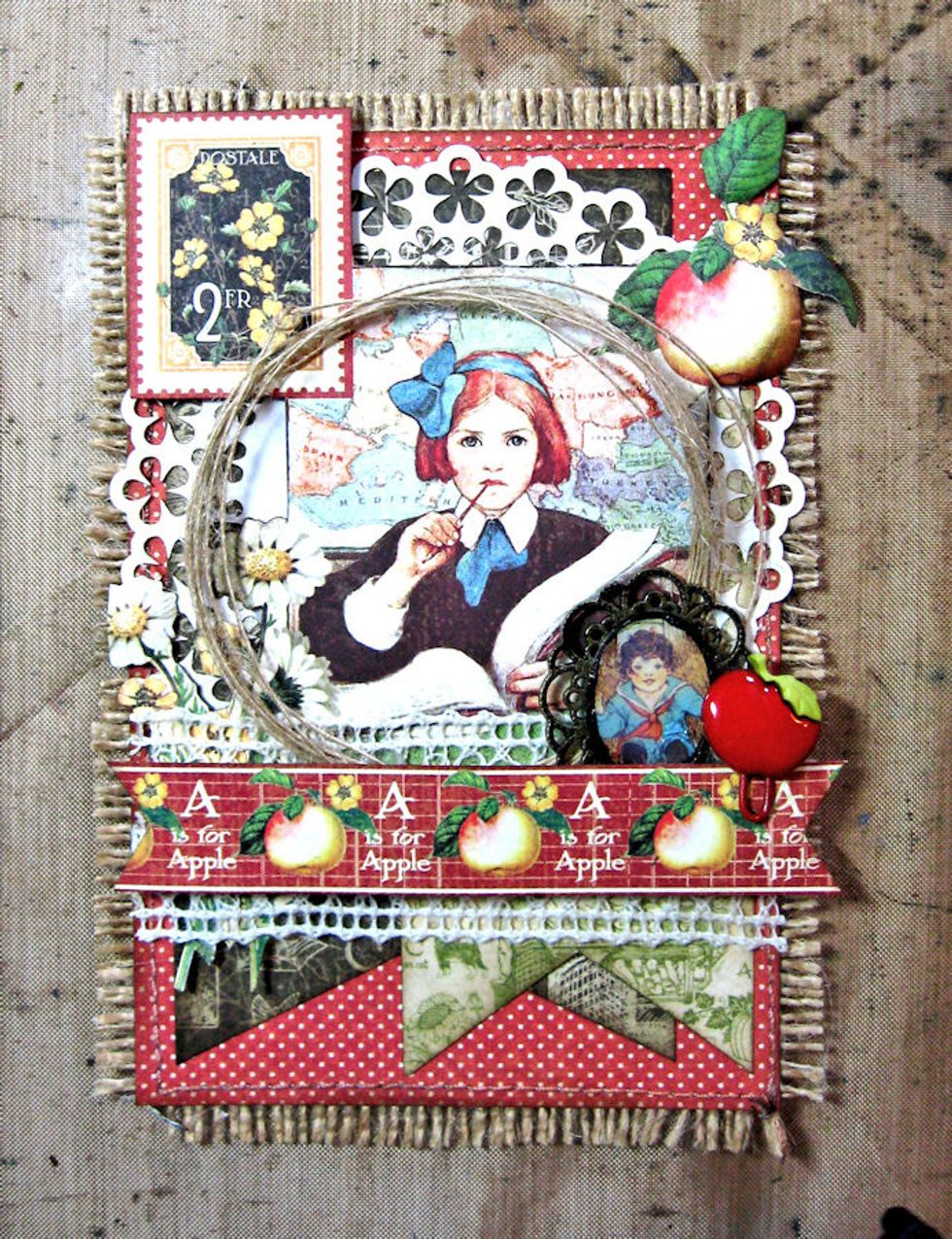 Cut apple border strip to width of card, making fishtail banners on each end. Glue apple button onto paper clip and attach to the border. Back border with waste chipboard or foam spacers and glue down