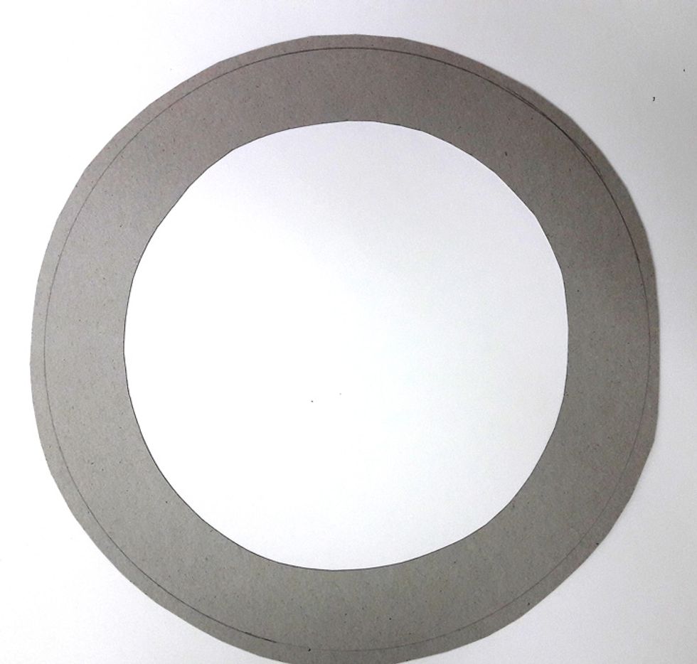 Cut chipboard into a circle. Decide the size of circle to match your hanging location. The circle doesn't have to be very accurate.