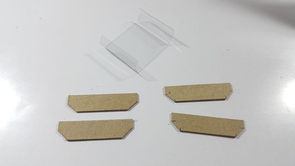 Cut chipboards 2"x1/2" for the top and bottom of the window, chop the corners, adhere 2 by 2. Then ready the acetate of 1-1/2" height, measure the chipboard and score the acetate to match.